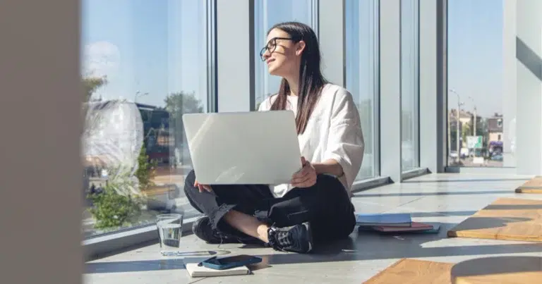 Dank Gleitzeit arbeitet eine Mitarbeiterin flexibel mit Laptop am Fenster